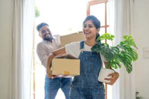 Indian young couple move the box into the home at new home.