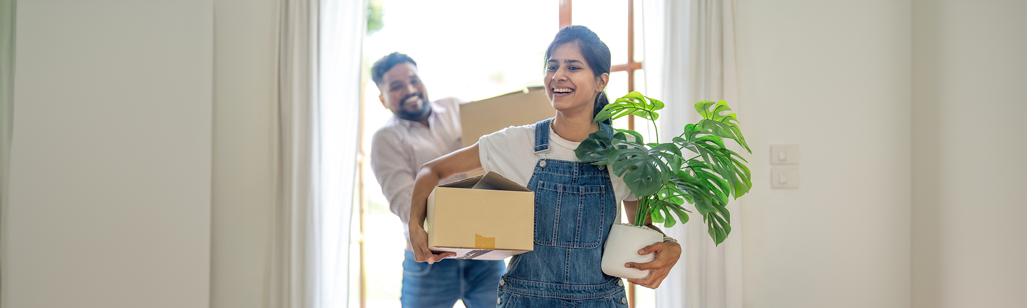 Young Indian couple move the box into their new home.